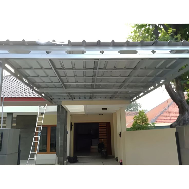 Kanopi Baja Ringan2 Kanopi carport modern dengan rangka kanopi baja ringan dan atap galvalum yang kuat dan tahan cuaca, dipasang di halaman rumah minimalis tropis.