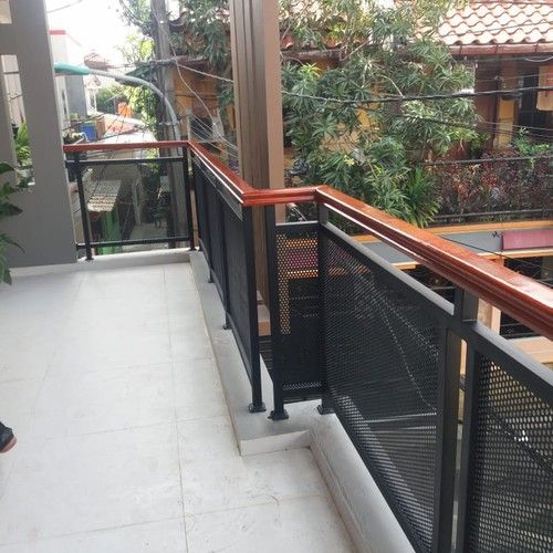 Pagar Balkon Kombinasi Besi & Kayu Desain pagar balkon rumah modern dengan kombinasi besi hollow hitam, plat perforated, dan railing kayu coklat – inspirasi pagar rumah kekinian untuk balkon lantai dua bergaya industrial minimalis.