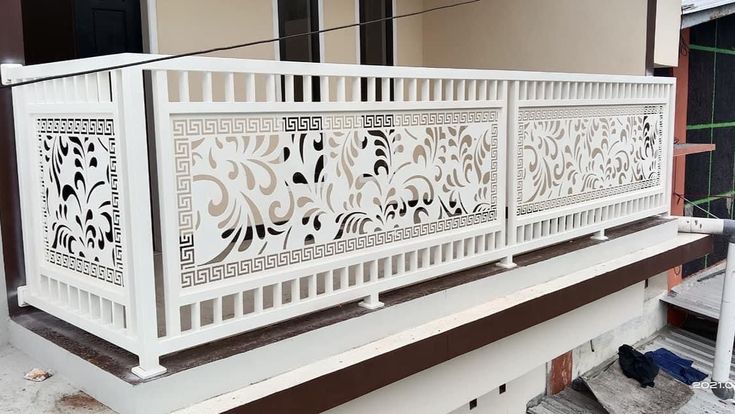 Pagar Balkon Motif Daun atau Floral Desain pagar balkon rumah minimalis modern warna putih dengan motif laser cut floral dan bingkai ornamen klasik – inspirasi pagar rumah elegan dan bersih untuk balkon lantai atas.